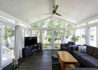 Solarium chaleureux avec rideaux aux fenêtres, toit cathédrale et ventilateur de plafond